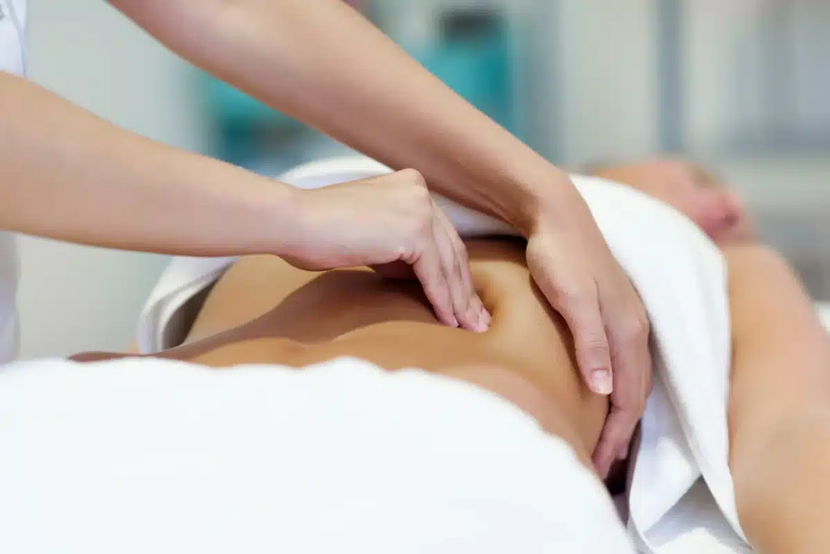 woman having abdomen massage by professional osteopathy therapist