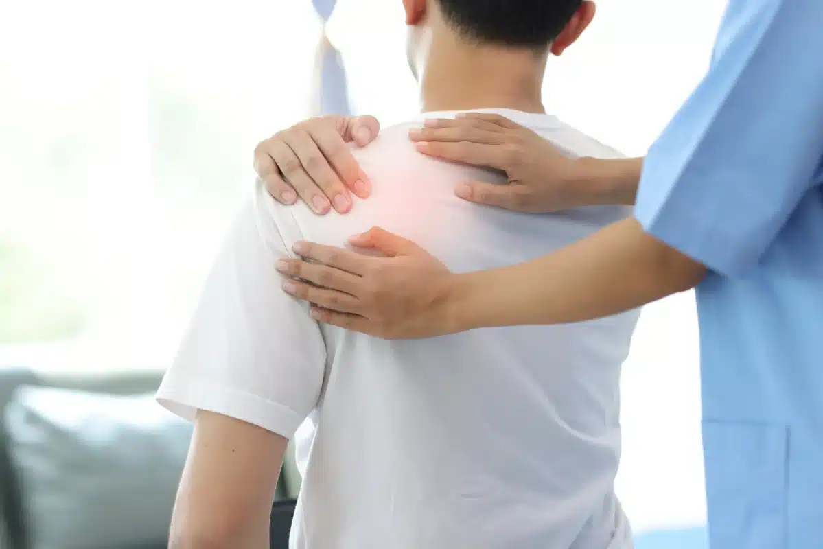 doctor diagnosing mans shoulder pain hospital examination room nurse doing massage physiotherapy treat patients shoulder